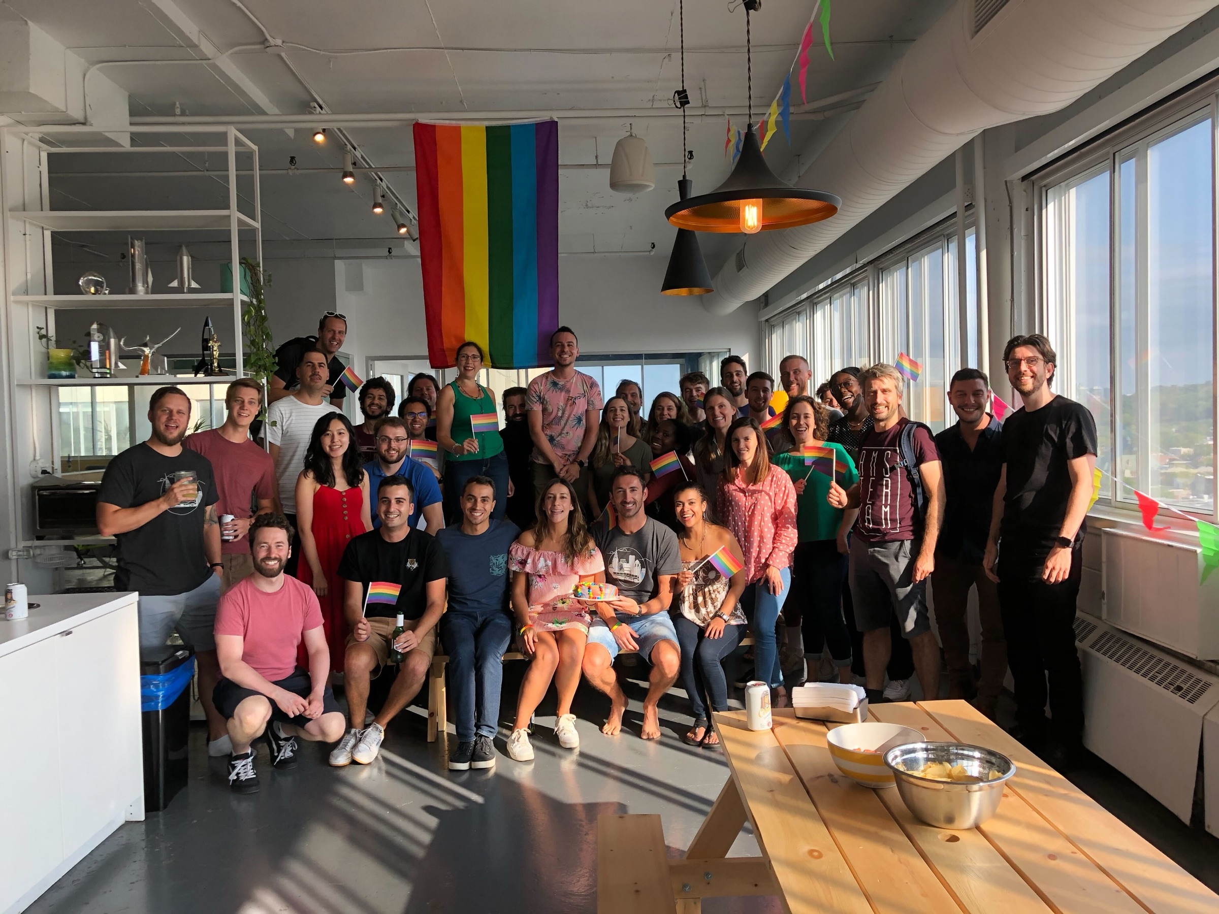 The team celebrating Pride together in the office, waving rainbow flags