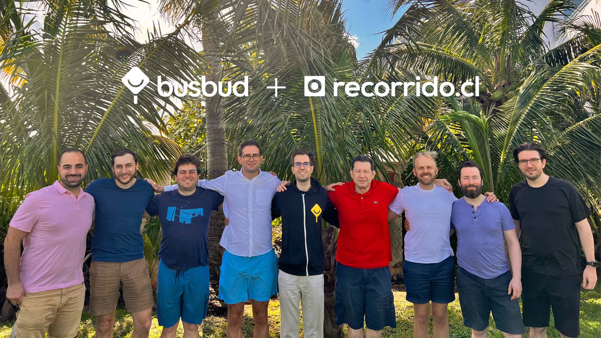 Members of the Busbud and Recorrido teams posing together outdoors under palm trees to mark the two companies joining forces