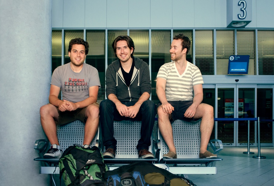 Busbud's three co-founders sitting together at an airport departure gate