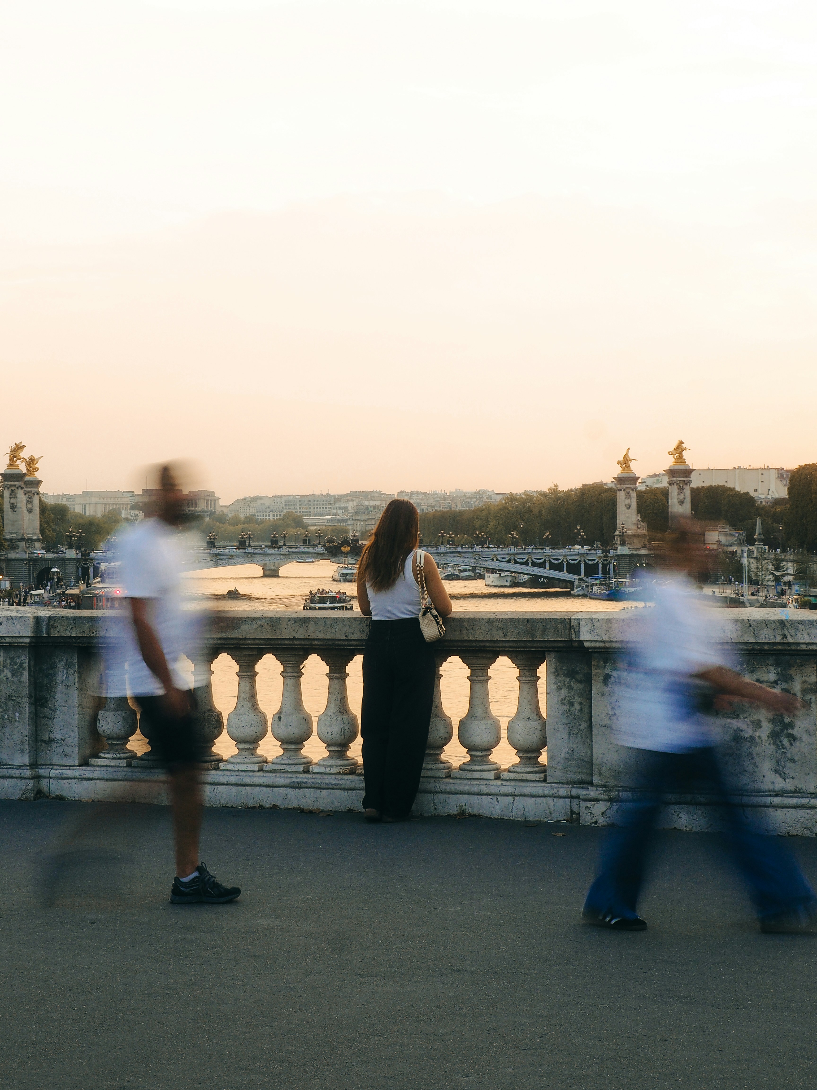 Pedestrians crossing a Seine bridge at sunset, motion blurred