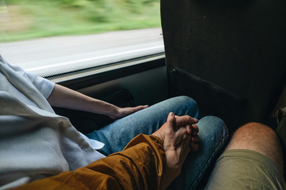 Close-up of two passengers' hands resting together on a bus seat