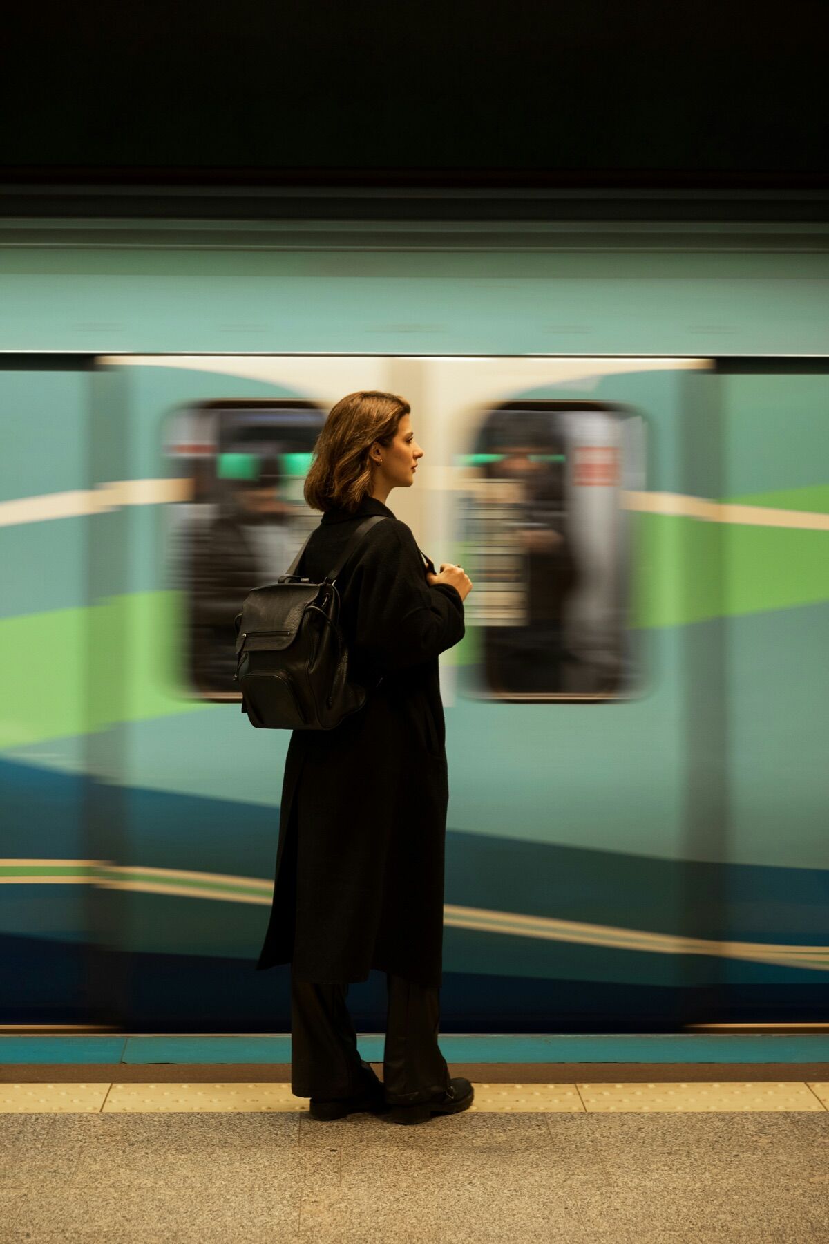 Passenger with a backpack waiting on a metro platform as a train passes