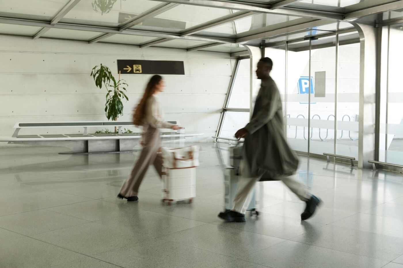 Two travelers walking through a bright modern transit terminal with luggage