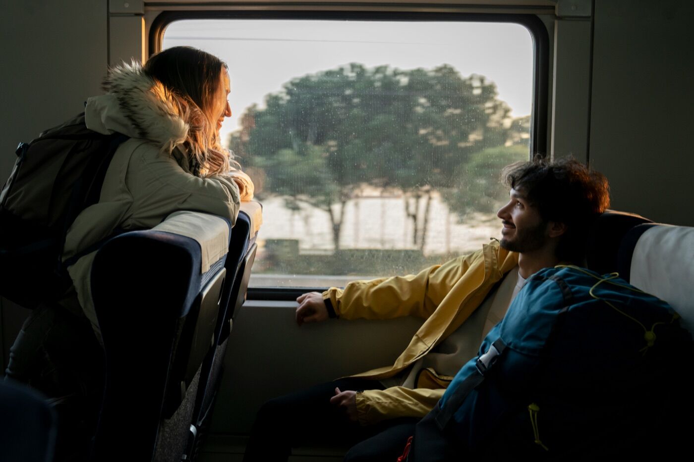 Two passengers sitting on a train looking out the window in golden afternoon light
